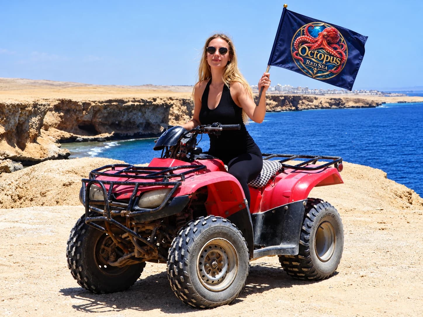 Woman on a quad bike overlooking the coast with an Octopus Red Sea flag